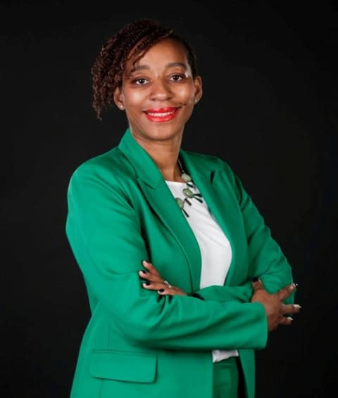 African woman smiling confidently in professional attire.