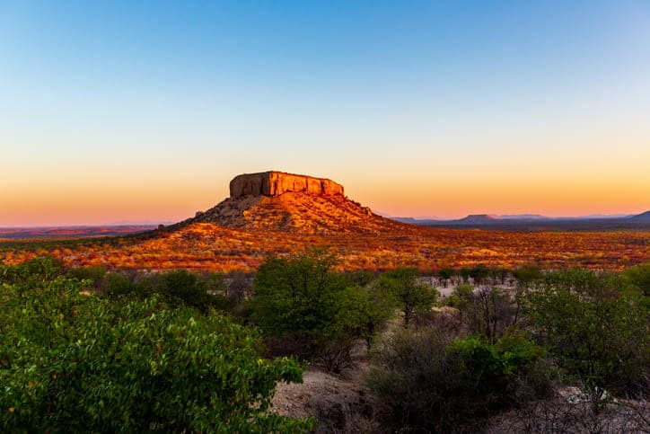 Namibian desert landscape with a prominent flat-topped mountain during sunset.