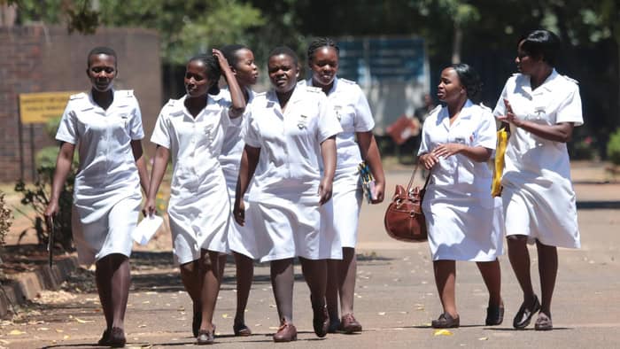 Group of young women in school uniforms walking outdoors in Africa.