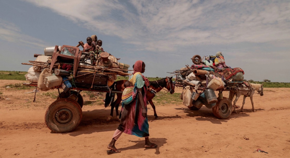 Refugees crossing desert with loaded carts in Darfur, Sudan.