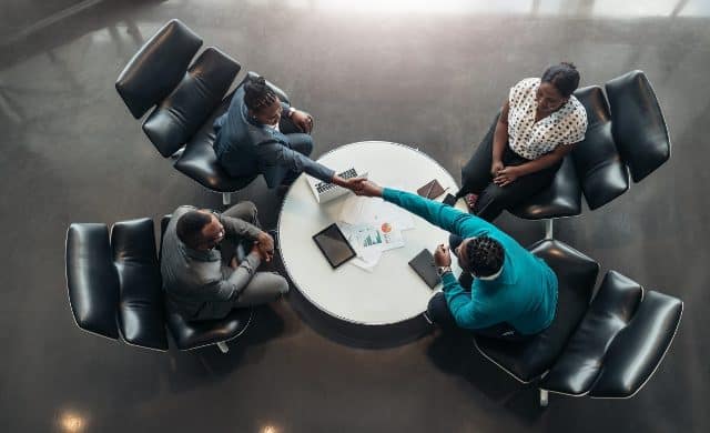 Business professionals shaking hands during a meeting in a modern conference room.
