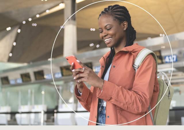 Young woman using mobile device at airport, symbolizing optimism among Kenyan SMEs.