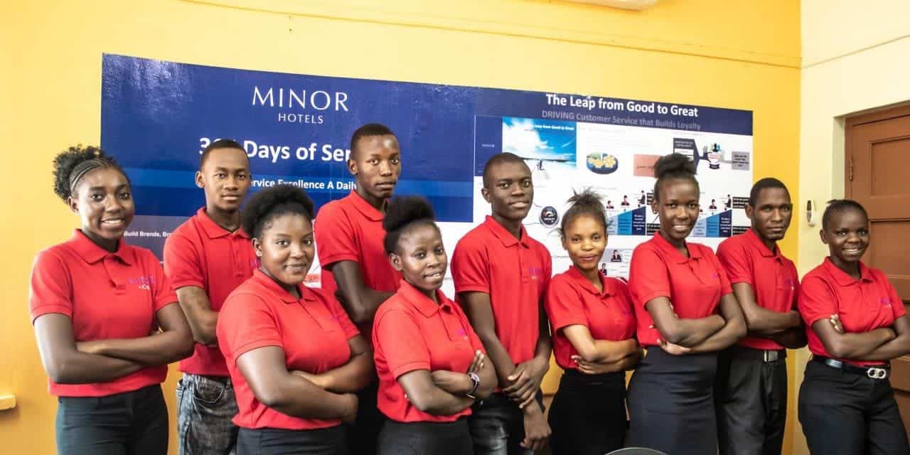Group of diverse hotel staff members in red uniforms at African hotel property.