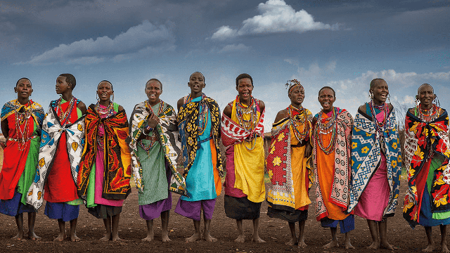 Group of African women in colorful traditional attire standing together outdoors.