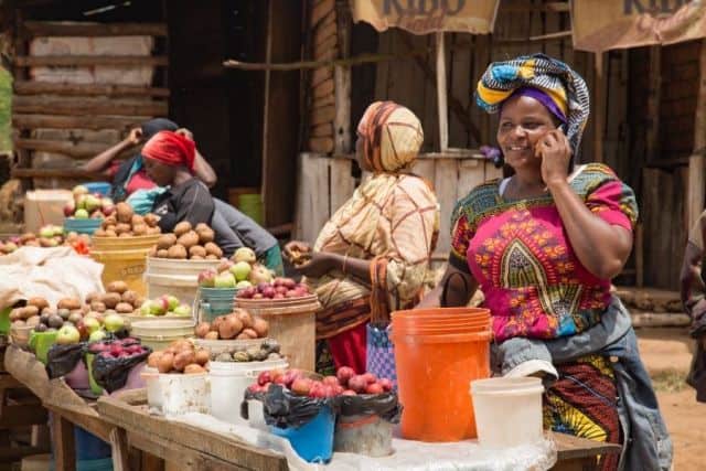 Market women selling fresh produce in an outdoor village market.