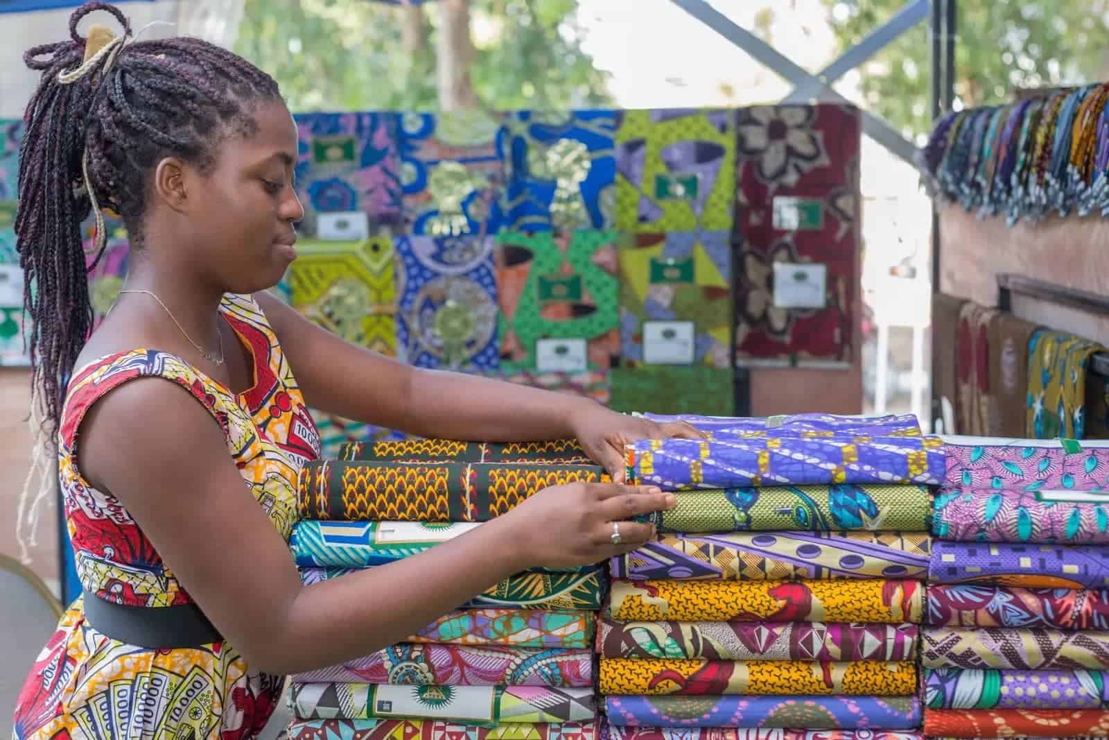 African woman selecting colorful textiles for small business growth.