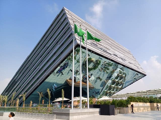 Eco-friendly building with green flags in front, symbolizing sustainability and climate action in Af.