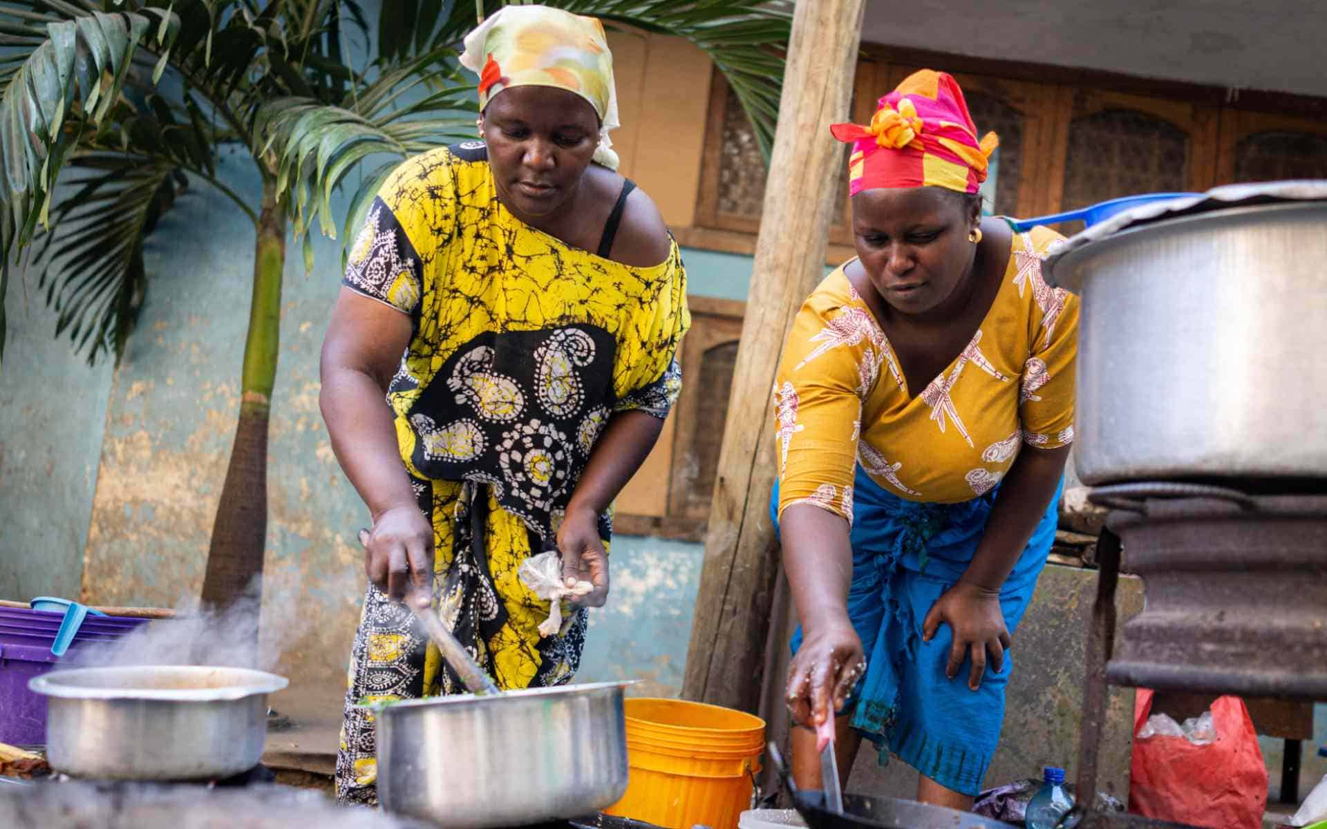 Women cooking traditional African dishes outdoors.