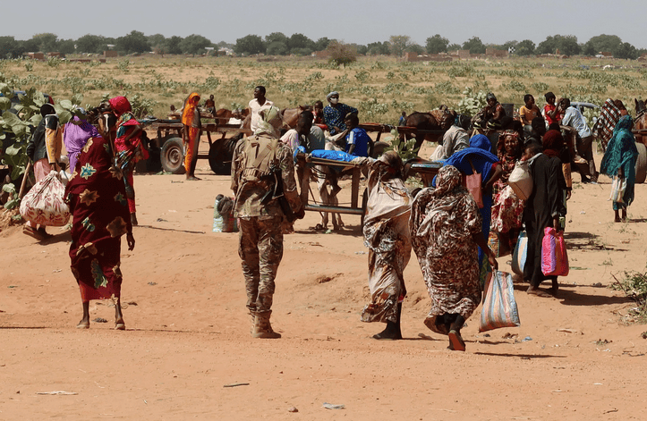 People fleeing conflict in Sudan with belongings, under a clear sky.