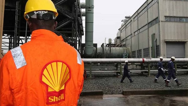 Oil industry workers in safety gear at an industrial plant.