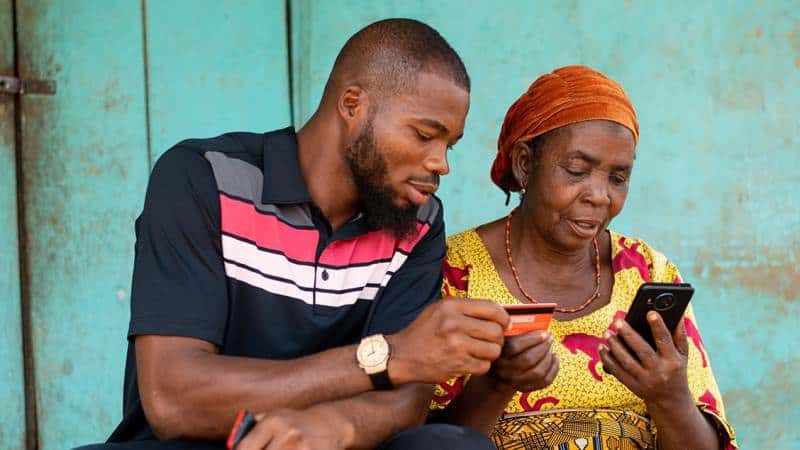Two African individuals using mobile phones for banking transactions.