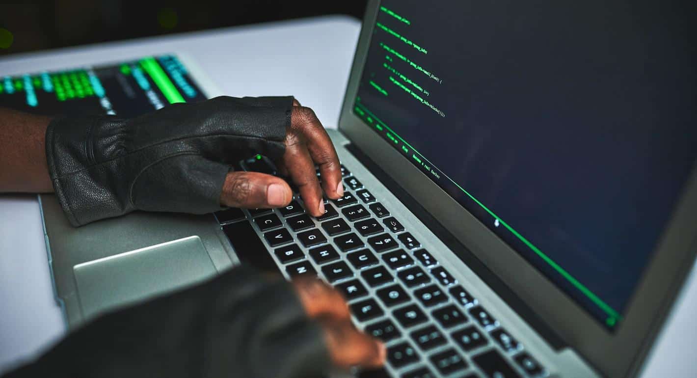 Hacker working on a laptop with cybersecurity code on screen.
