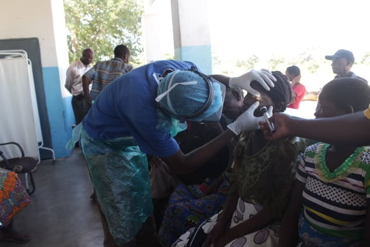 Healthcare worker performs eye examination on a patient in Zambia.