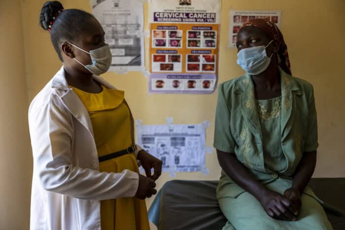 Two women discussing cervical cancer prevention at a clinic in Kenya, wearing masks.