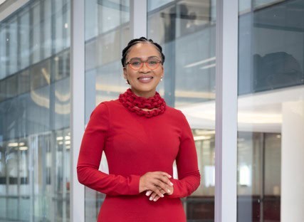 Woman in red dress smiling in modern office building, representing logistics sector reform in Africa.