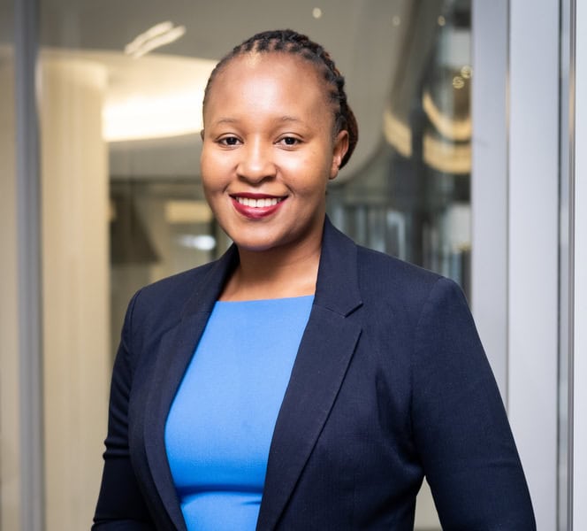 African woman in business suit smiling confidently.