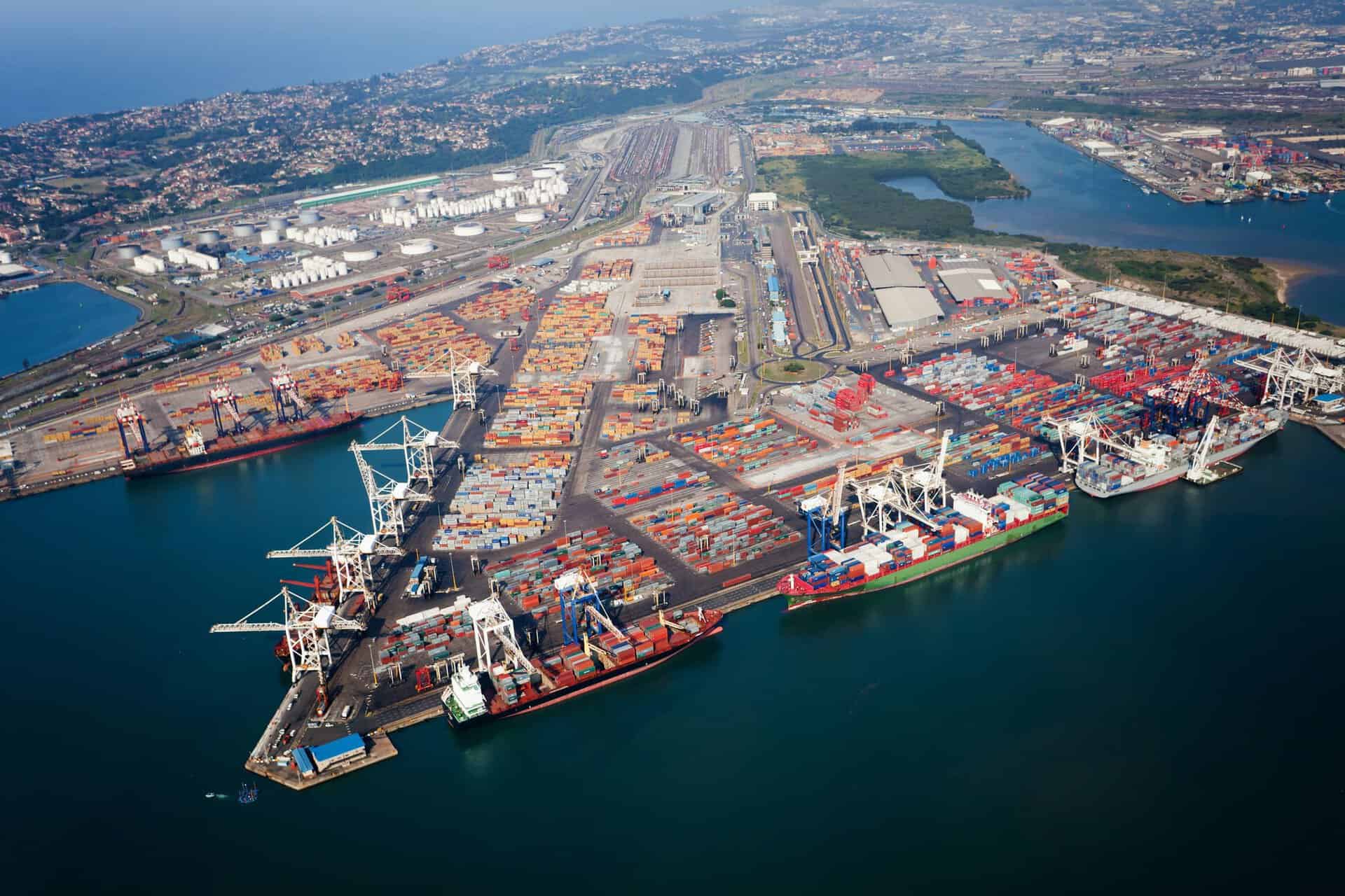 Aerial view of a busy port showcasing cargo ships, containers, and cranes symbolizing Africa-Gulf ec.