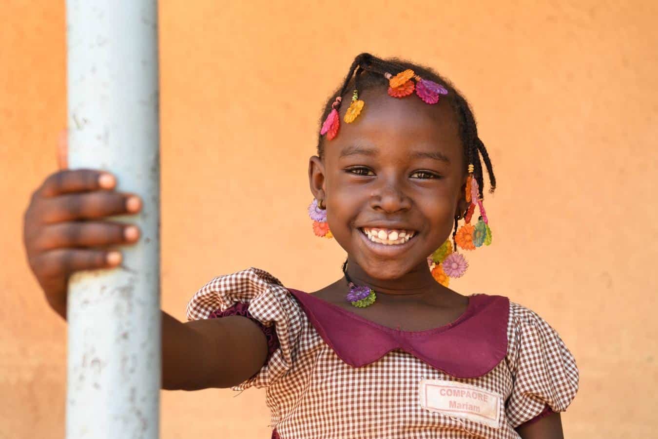 Child smiling with colorful beads, celebrating African children's rights and happiness.