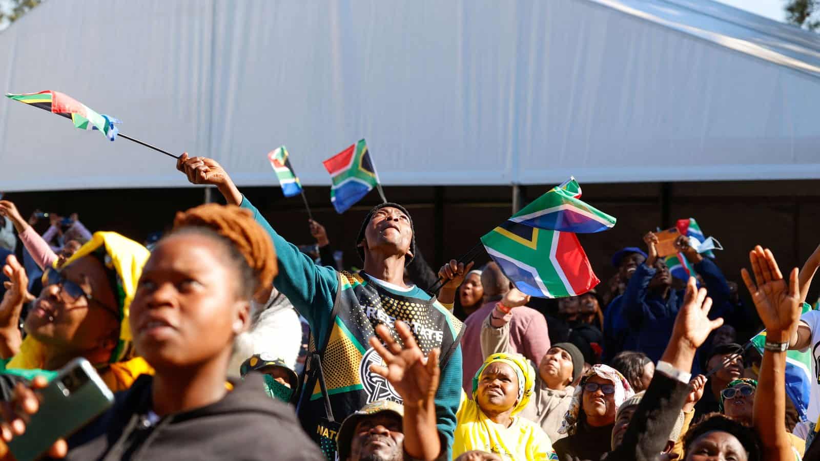 An image of South Africans celebrating, holding flags, and showing unity amid political challenges.