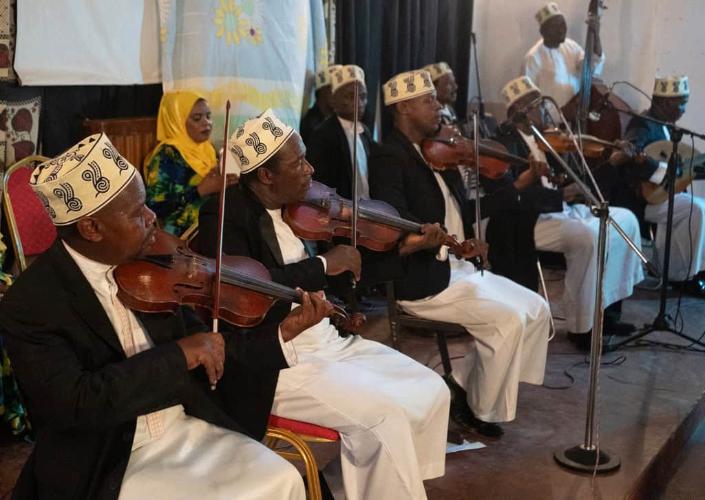 Traditional Tanzanian musicians performing with violins and drums during a cultural immersion event.