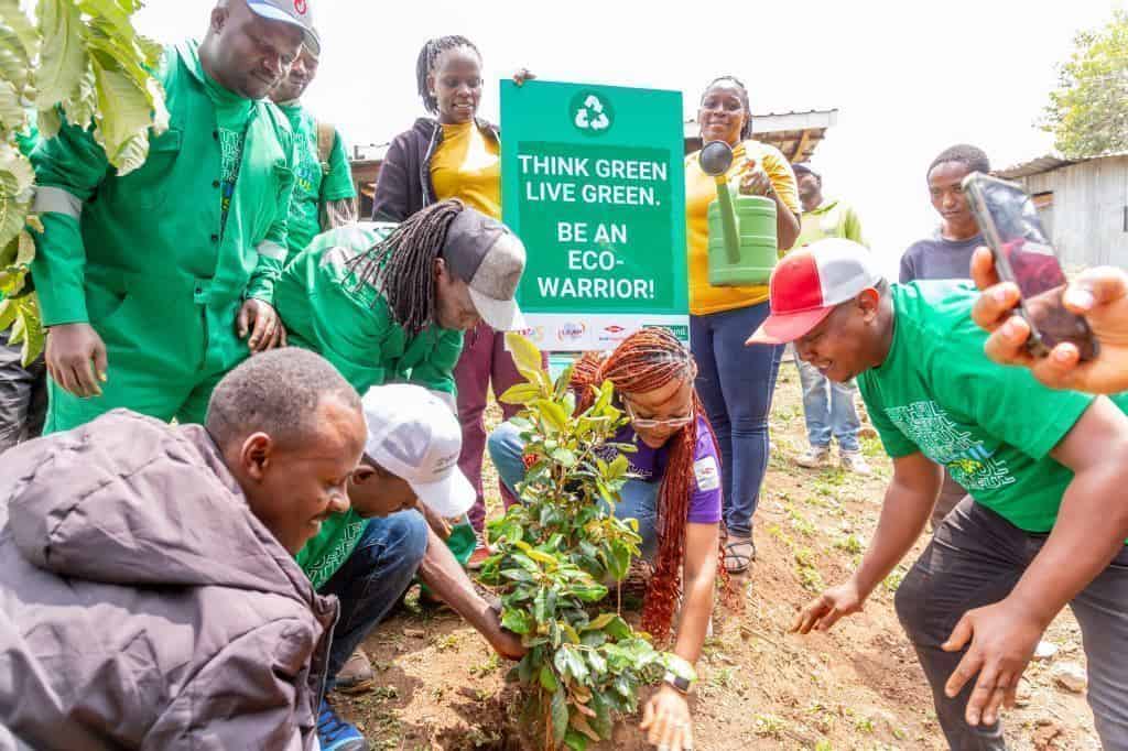 Youth planting a tree with community members promoting environmental sustainability in South Africa.