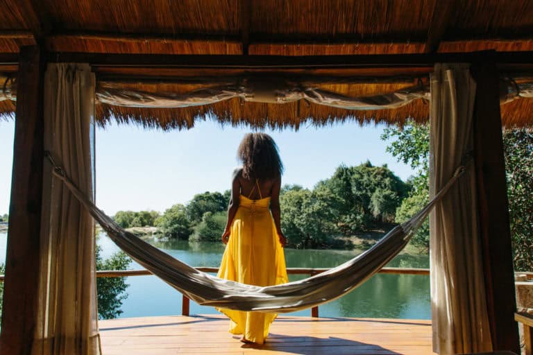 Woman relaxing in a hammock overlooking a river in Africa for solo travelers.