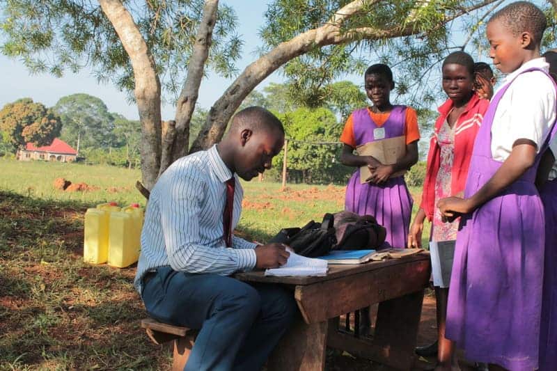 Young African students engaging with a teacher outdoors to promote leadership and education developm.