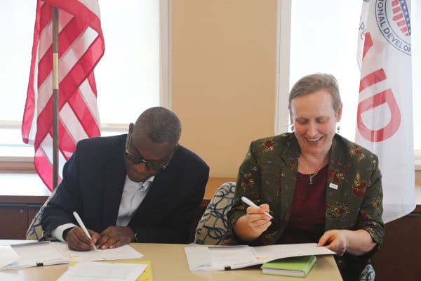 African and American officials signing agreement.