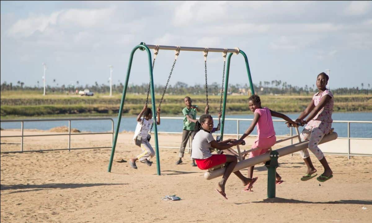 Children playing on a swing set in an outdoor playground in Africa.