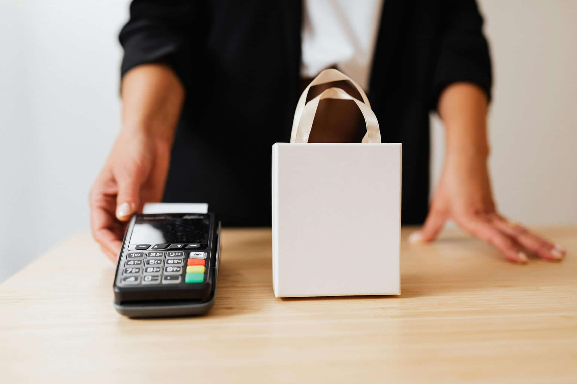 Contactless payment terminal and shopping bag on table.