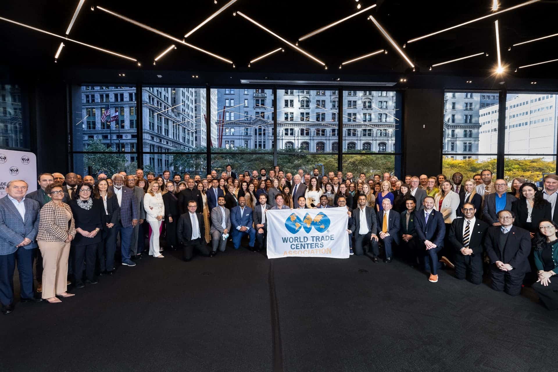 Trade forum participants holding WTCA banner in modern conference space.
