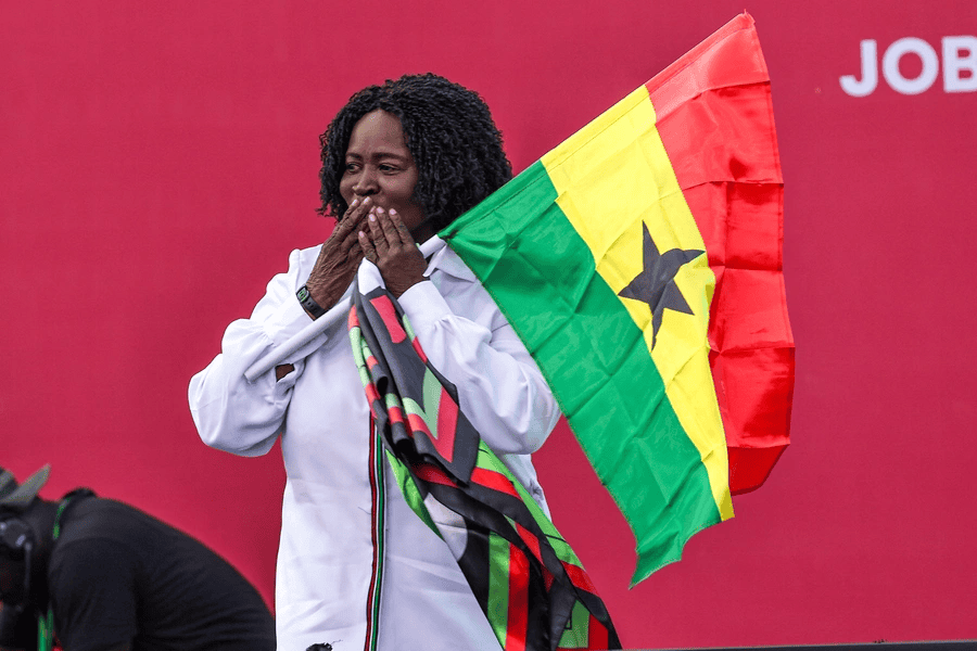 Naana Jane Opoku-Agyemang holding Ghana flag, celebrating historic election victory.