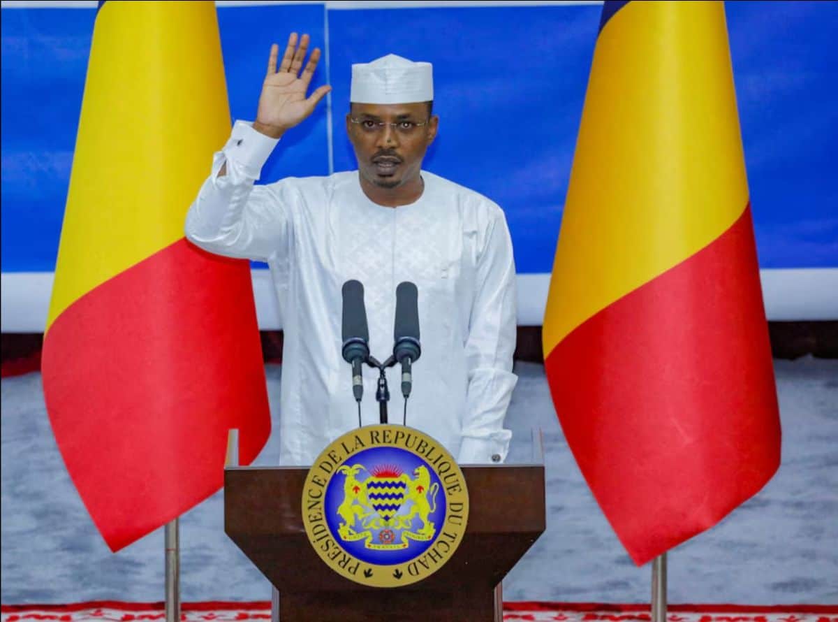 Chad president speaking at podium with flags, emphasizing leadership and national pride.