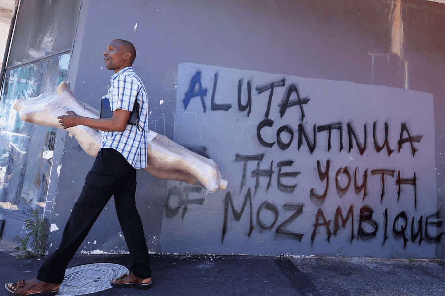 Young man walking past graffiti on wall in Mozambique, highlighting youth activism.