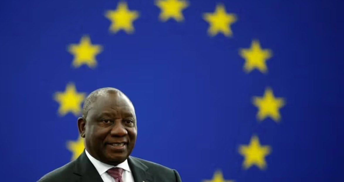 DRC official speaking with EU flag in background, highlighting regional race issues.
