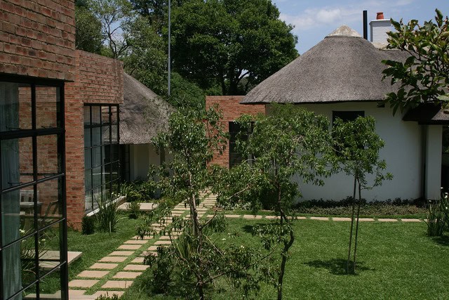 Beautiful African traditional houses with thatched roofs and lush gardens.