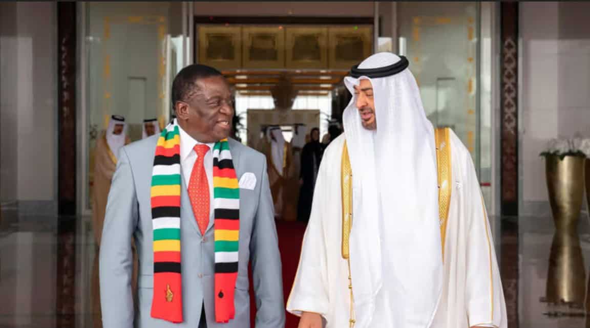 Two men in traditional and formal attire greeting each other at a luxurious hotel entrance in Africa.