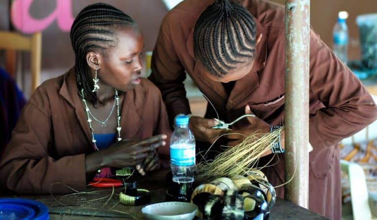 Two African women working on a craft project, showcasing entrepreneurship and innovation.