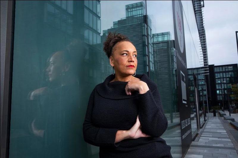 Modern woman standing outside in an urban environment with glass buildings in the background.