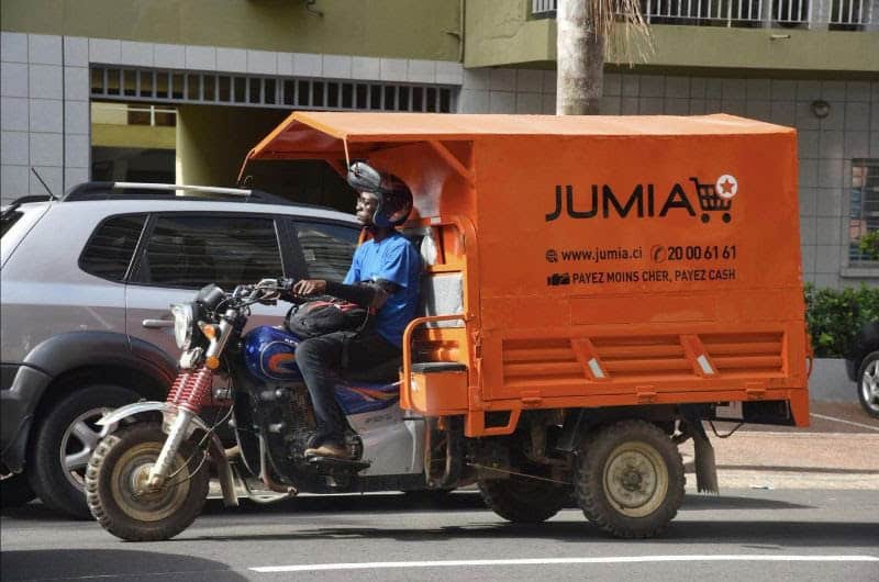 African delivery motorcycle with Jumia branding on city street.