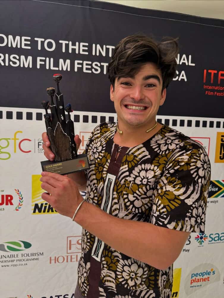 Young man holding a trophy at Africa Tourism Film Festival, celebrating South African short film suc.
