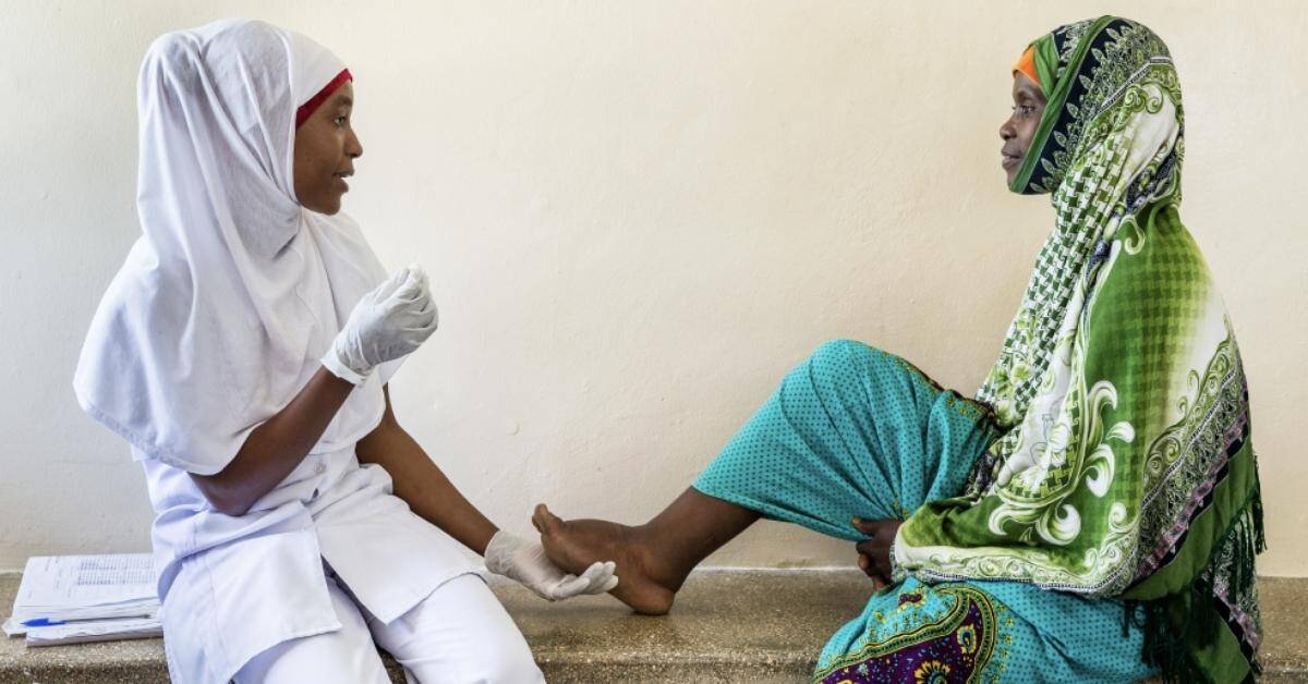 Healthcare worker testing a woman for malaria in Africa.