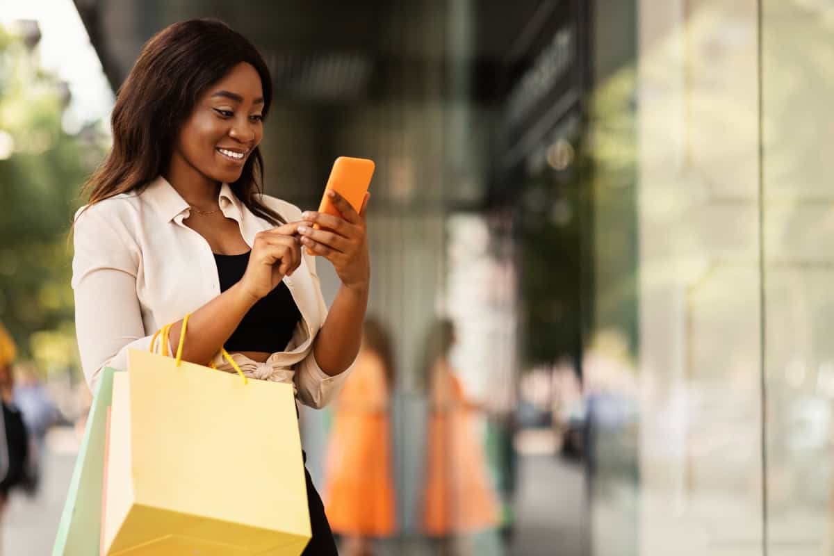Woman using smartphone for beauty shopping in an urban setting.