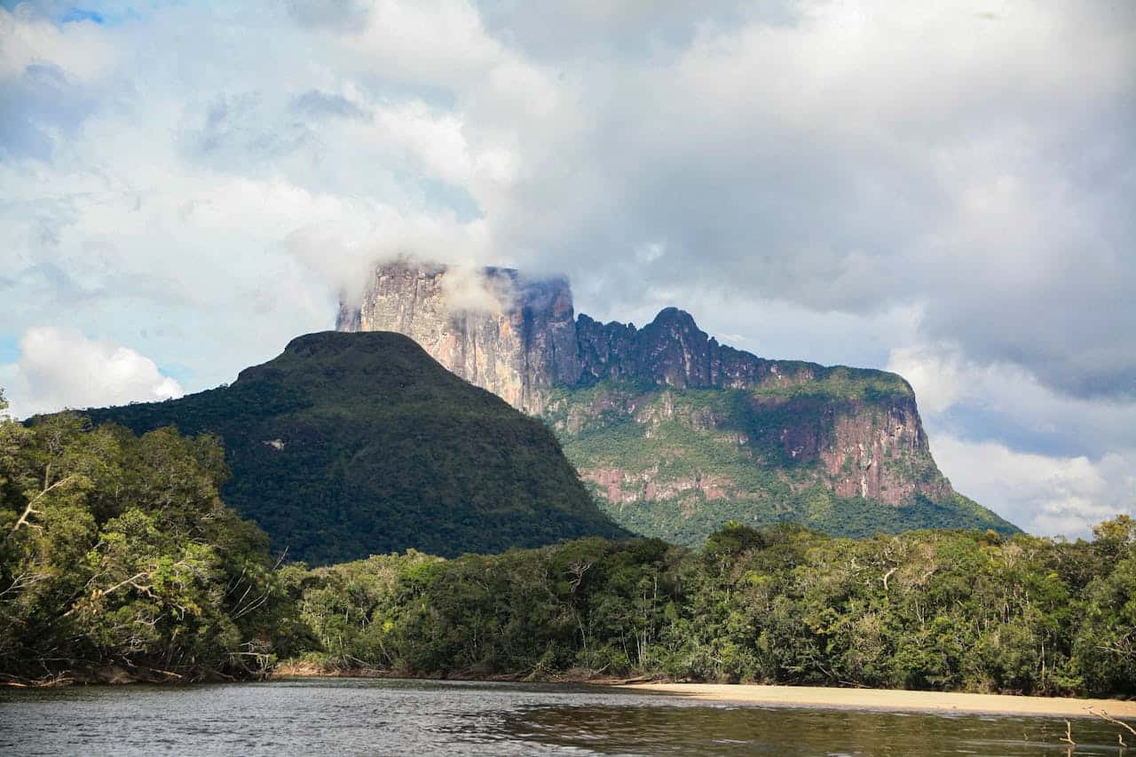 Scenic view of a mountain surrounded by lush greenery and a river in the foreground, emphasizing Afr.