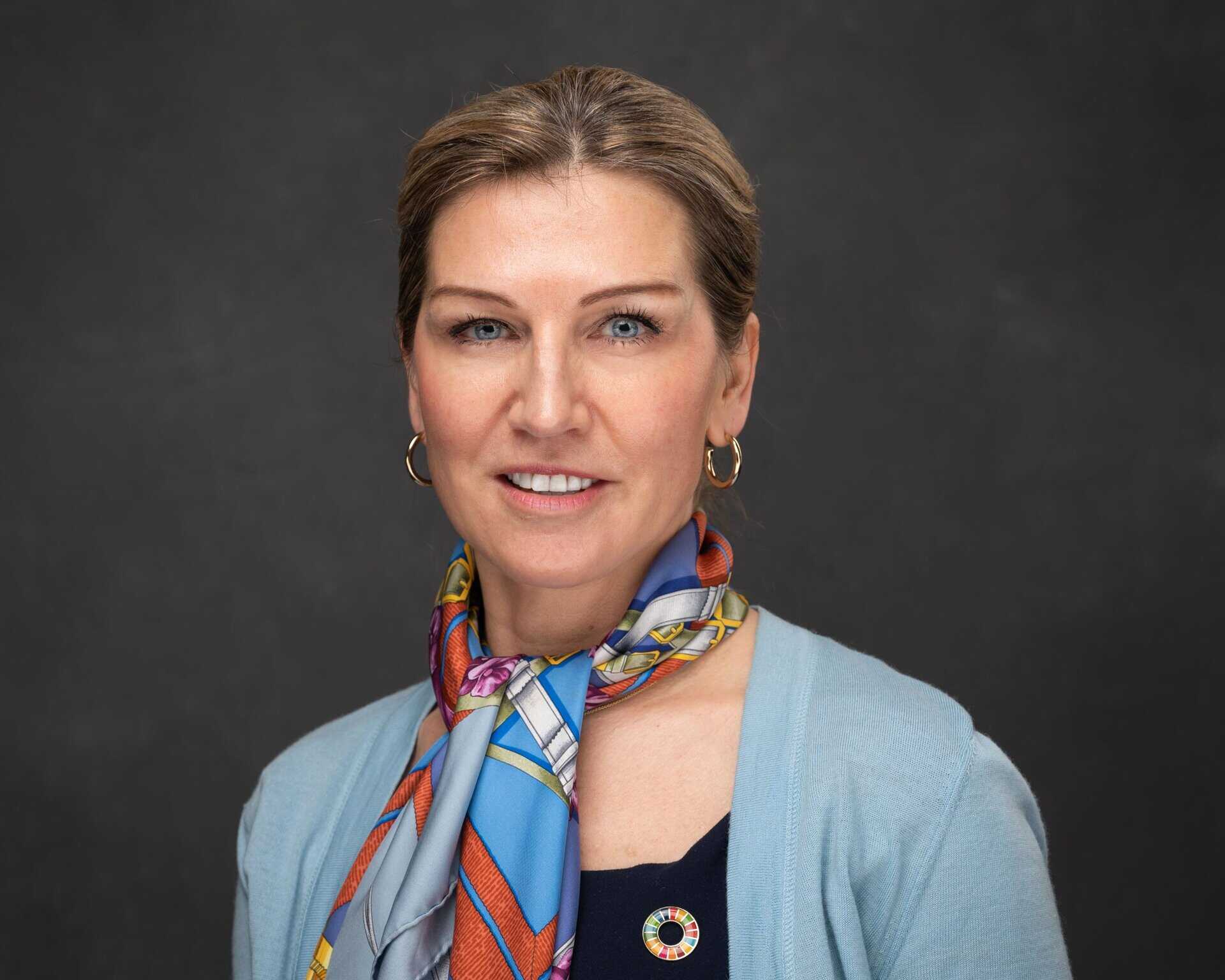 African woman smiling, wearing a colorful scarf, representing women in tech initiatives.