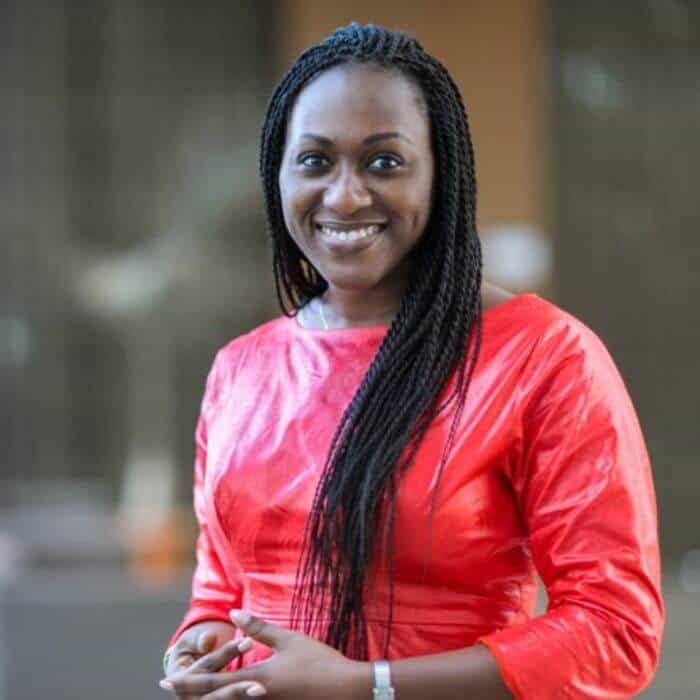 African woman smiling in red dress, representing research and health initiatives in Africa.