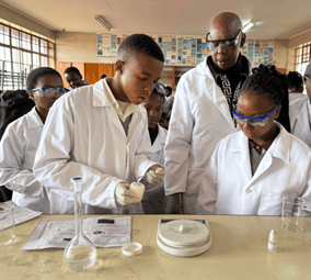 Students conducting science experiments in a classroom with teacher supervision.