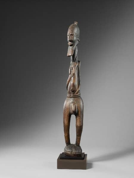 African wooden sculpture with detailed carvings and elongated form.