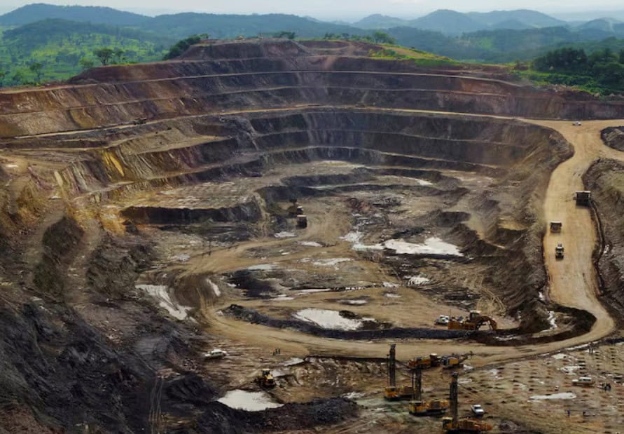 Mining quarry in Africa with terraced layers and heavy machinery for mineral extraction.