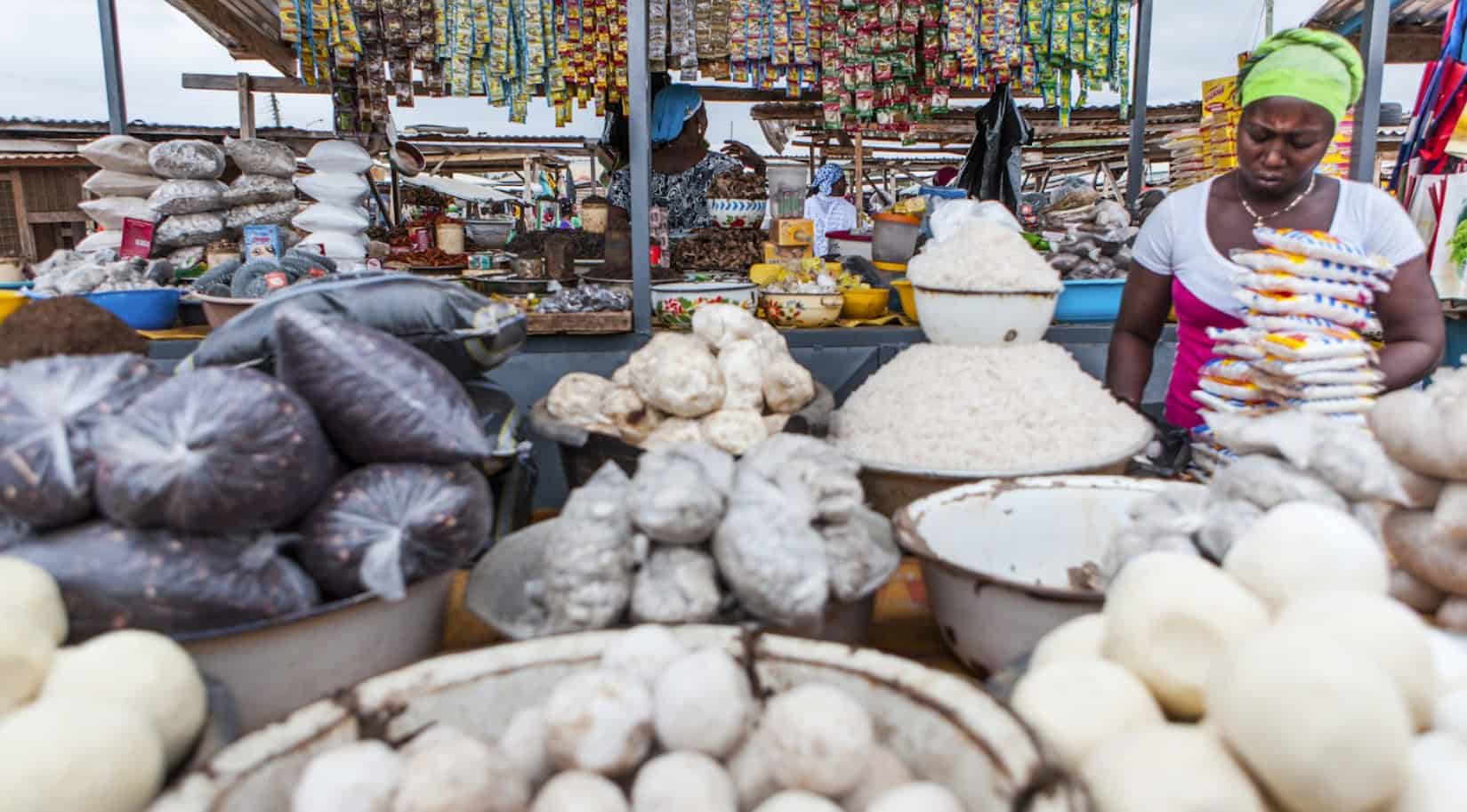 Vendors selling traditional African food products at a bustling market.